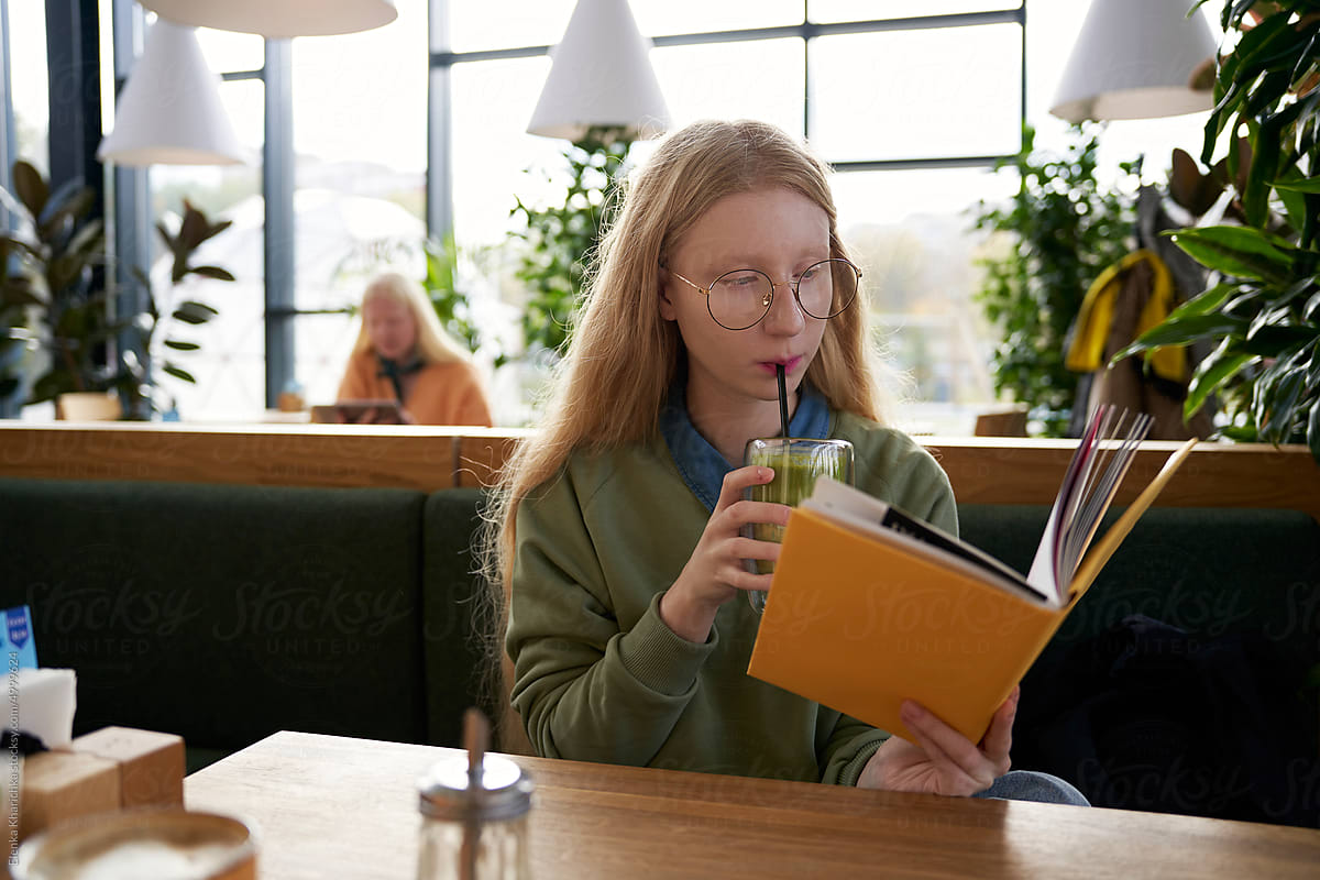 An albino student reading a book in a café