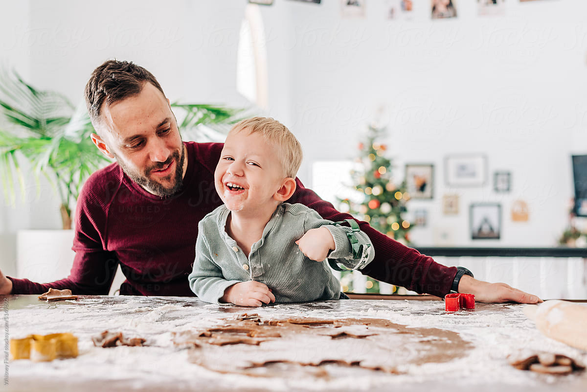 Laughing child and father bake gingerbread cookies