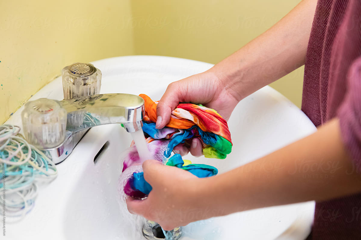Teen unwrapping and rinsing dye from a tie dyed t-shirt