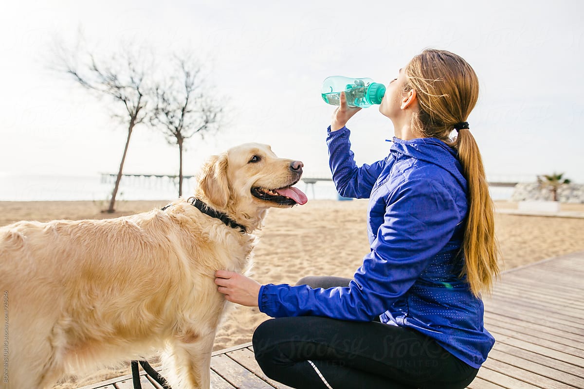 Runner woman with her dog drinking water after workout.