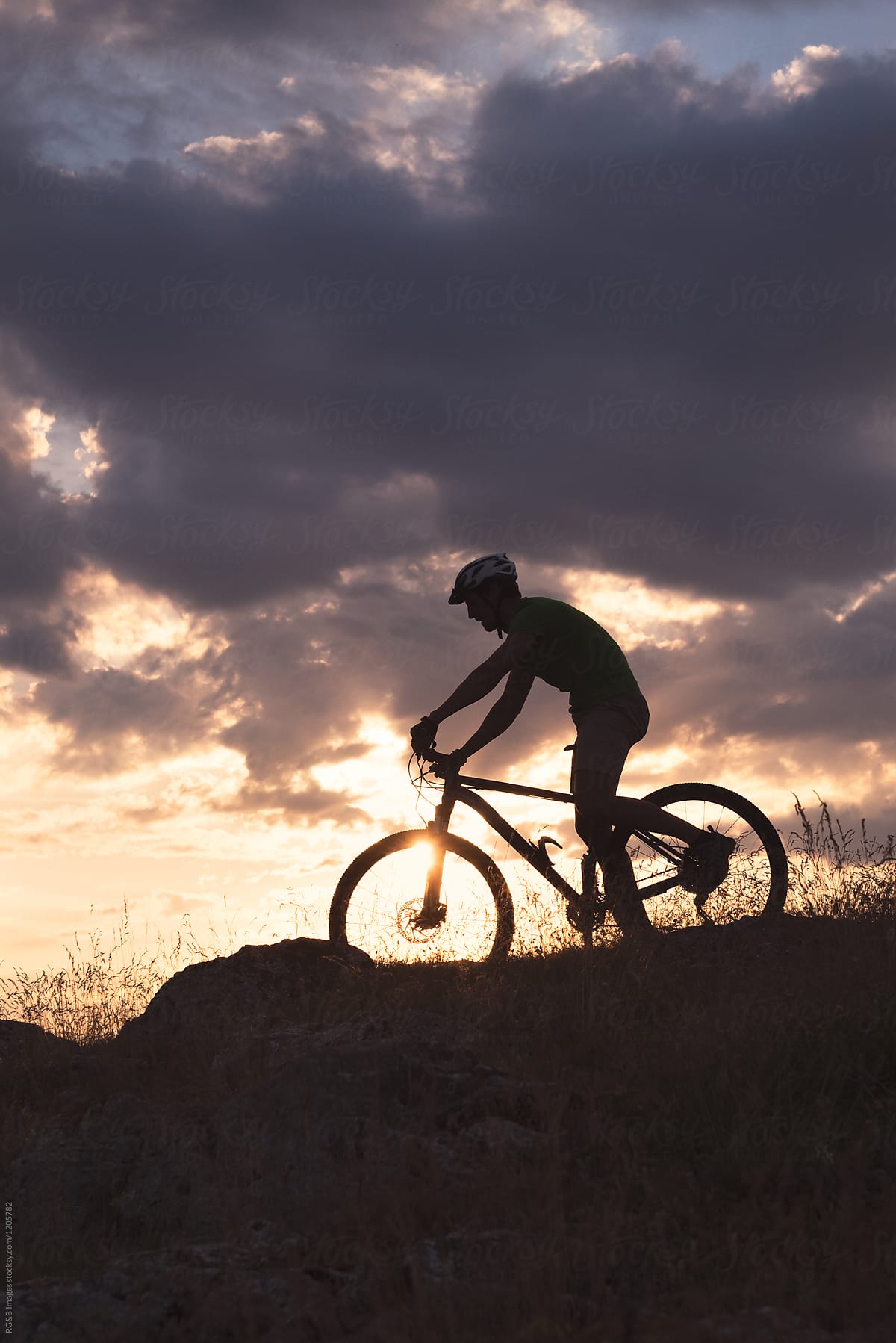 Sportsman silhouette riding downhill MTB on hills outdoor