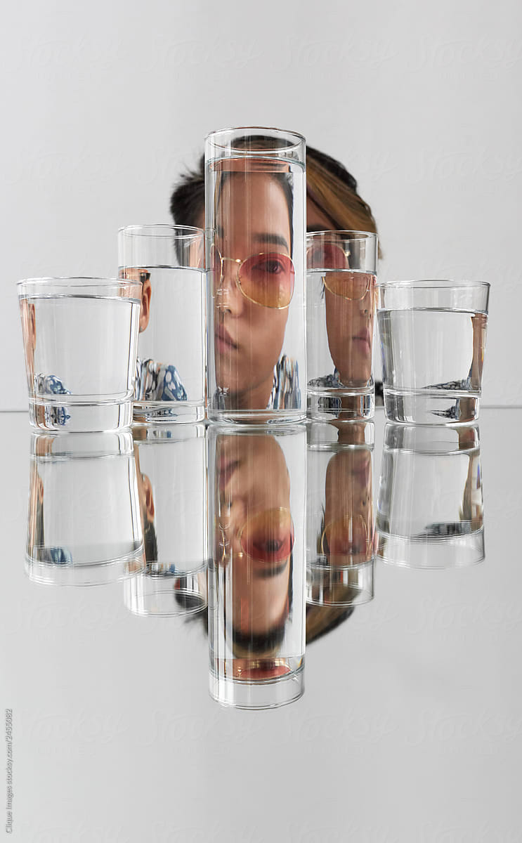 Asian woman distorted through glasses with water