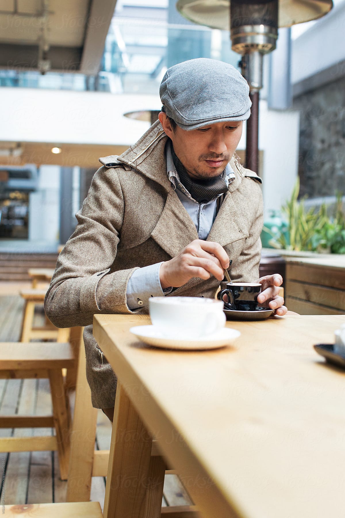 Good-Looking Young Asian Man Having Espresso in Bright Café