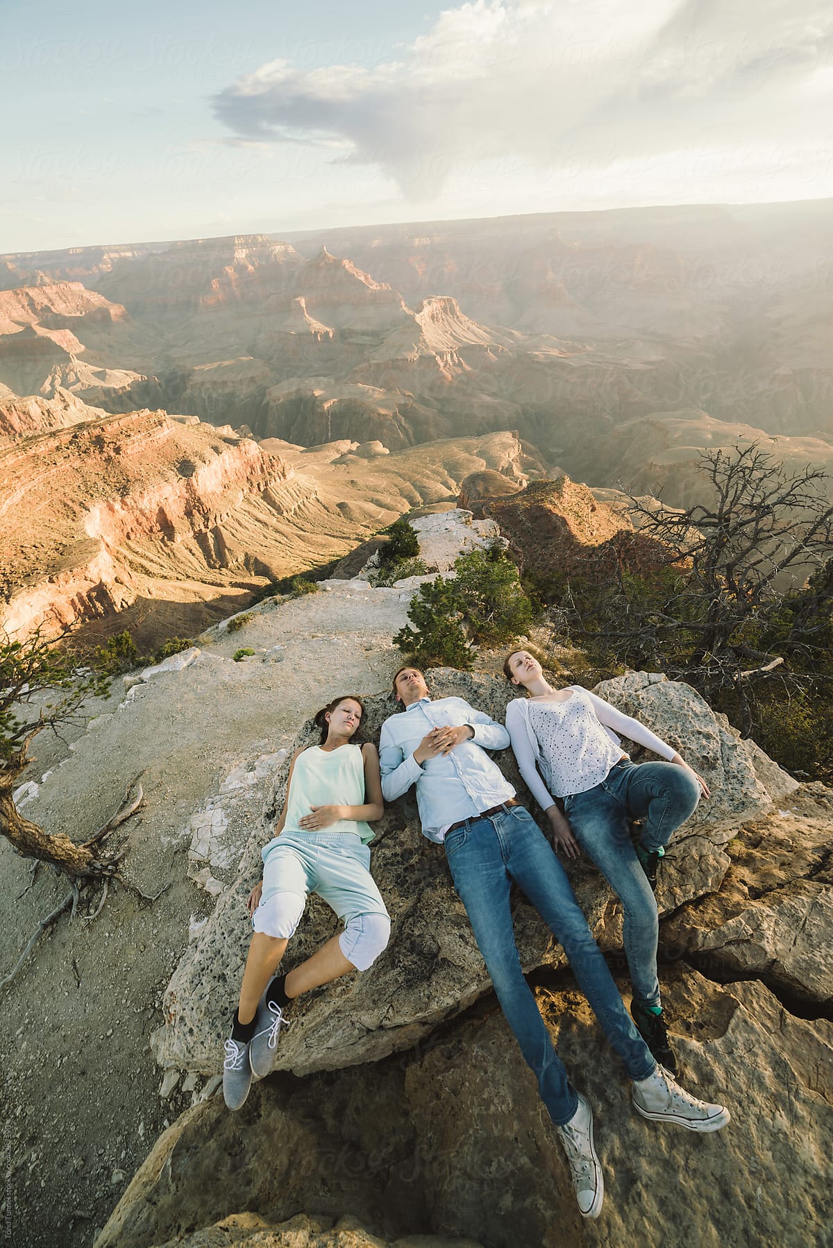 A group of friends lying on a cliff at Grand Canyon