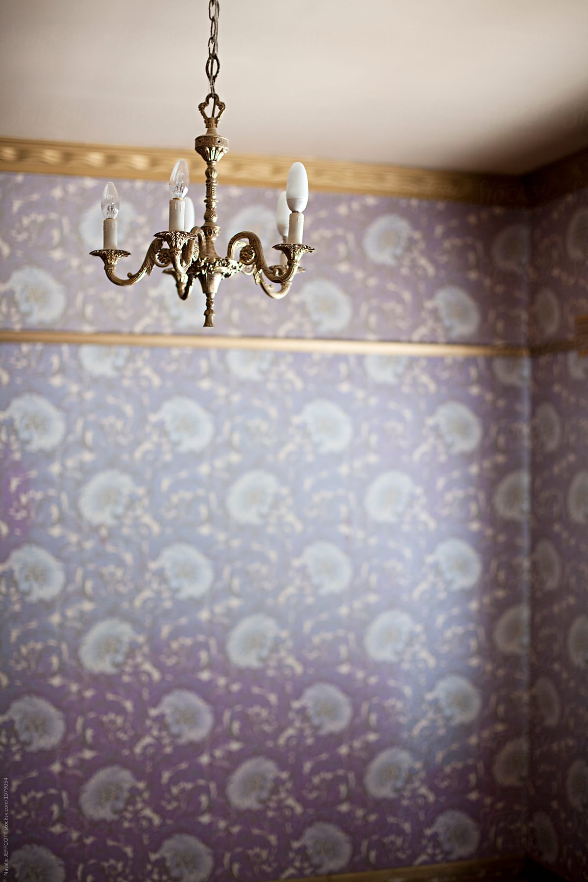 retro chandelier hanging in empty room with purple wallpaper