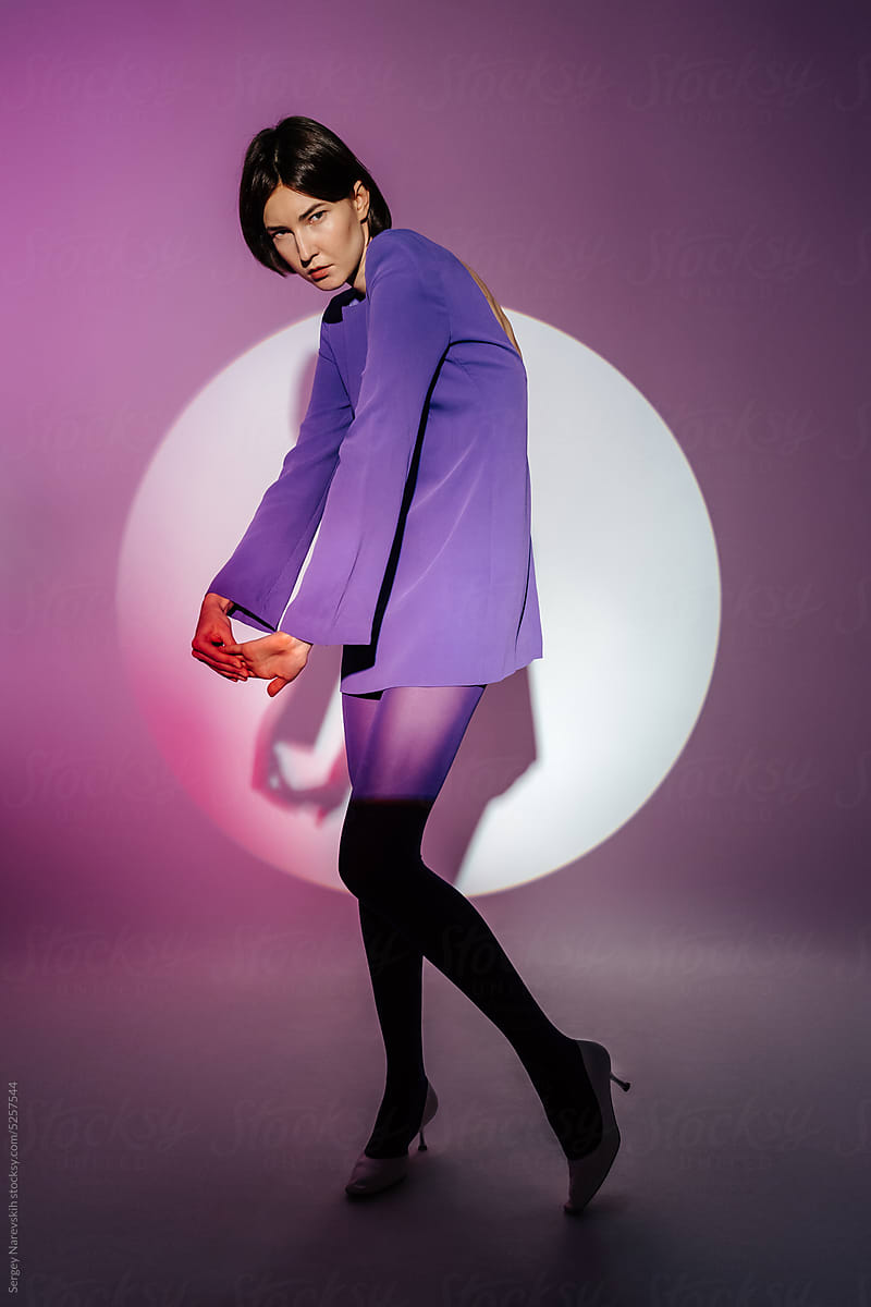 Female model in purple dress standing rounding back