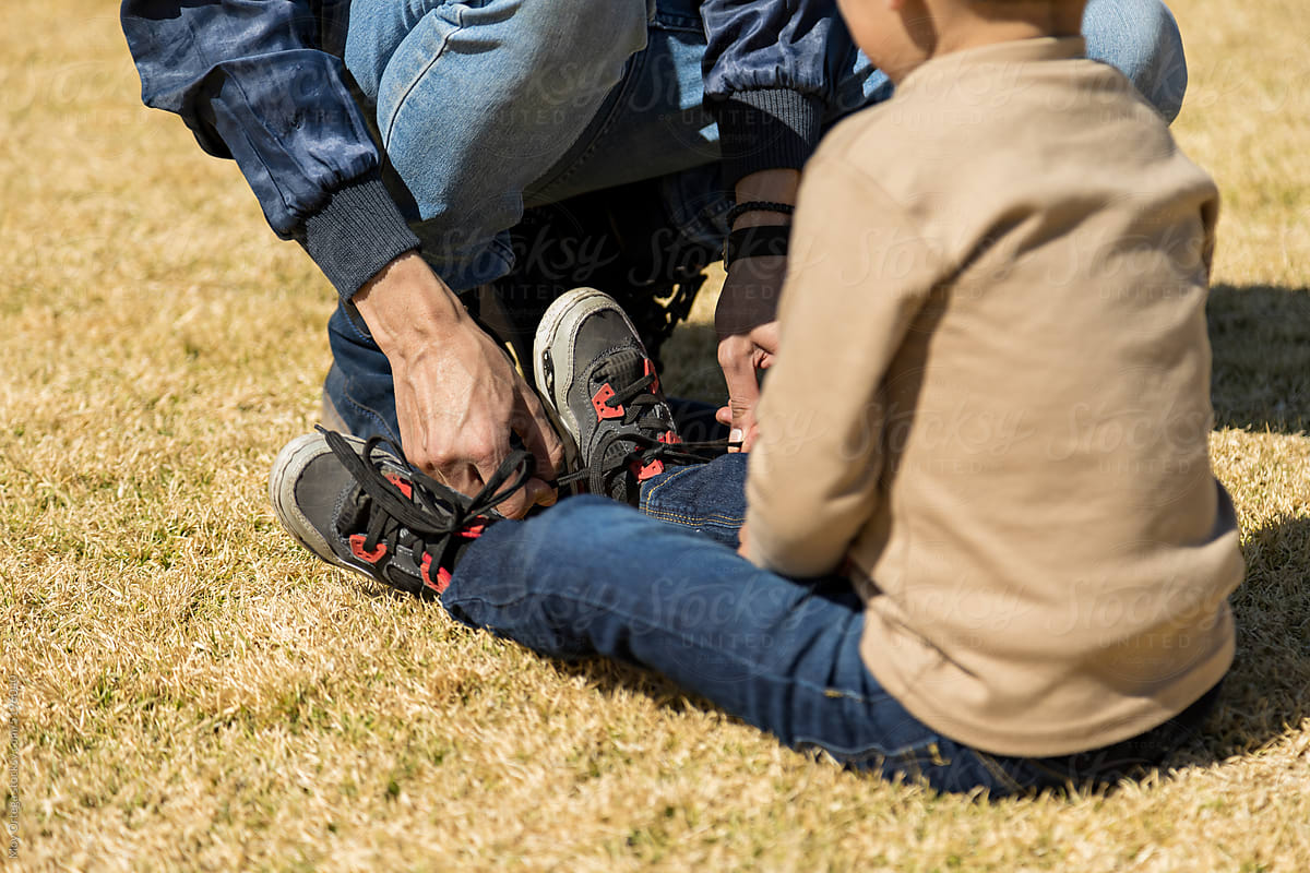 Close Up Of Father Helping His Son To Tie His Shoelaces