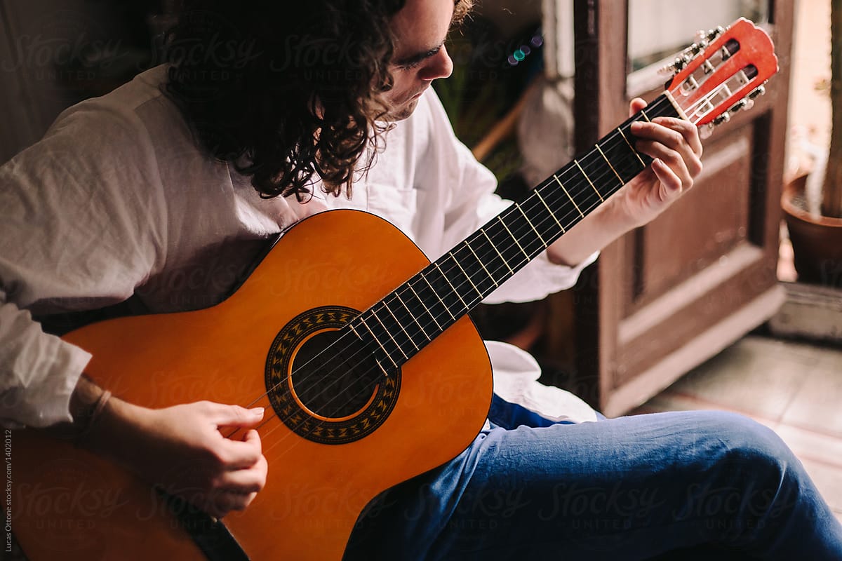 Young bohemian man playing acoustic guitar