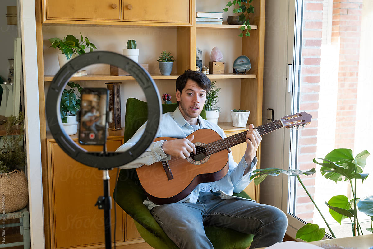 Man shooting a video playing guitar at home