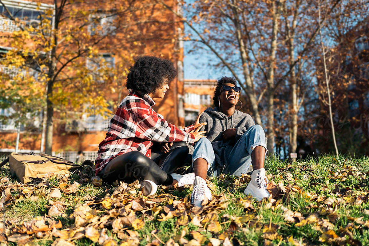 Content black girlfriends enjoying time in autumn park