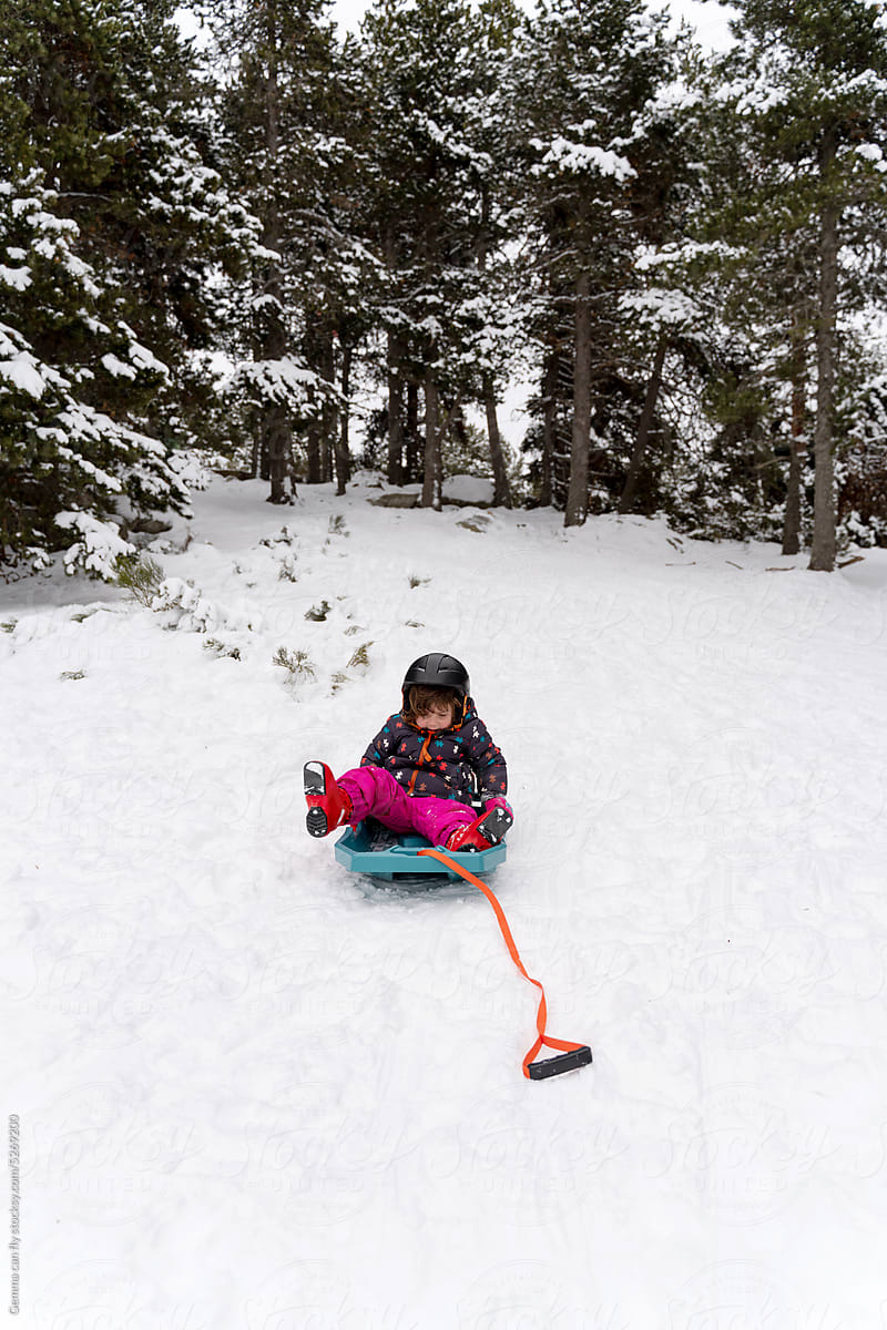 Girl playing with snow sled in winter