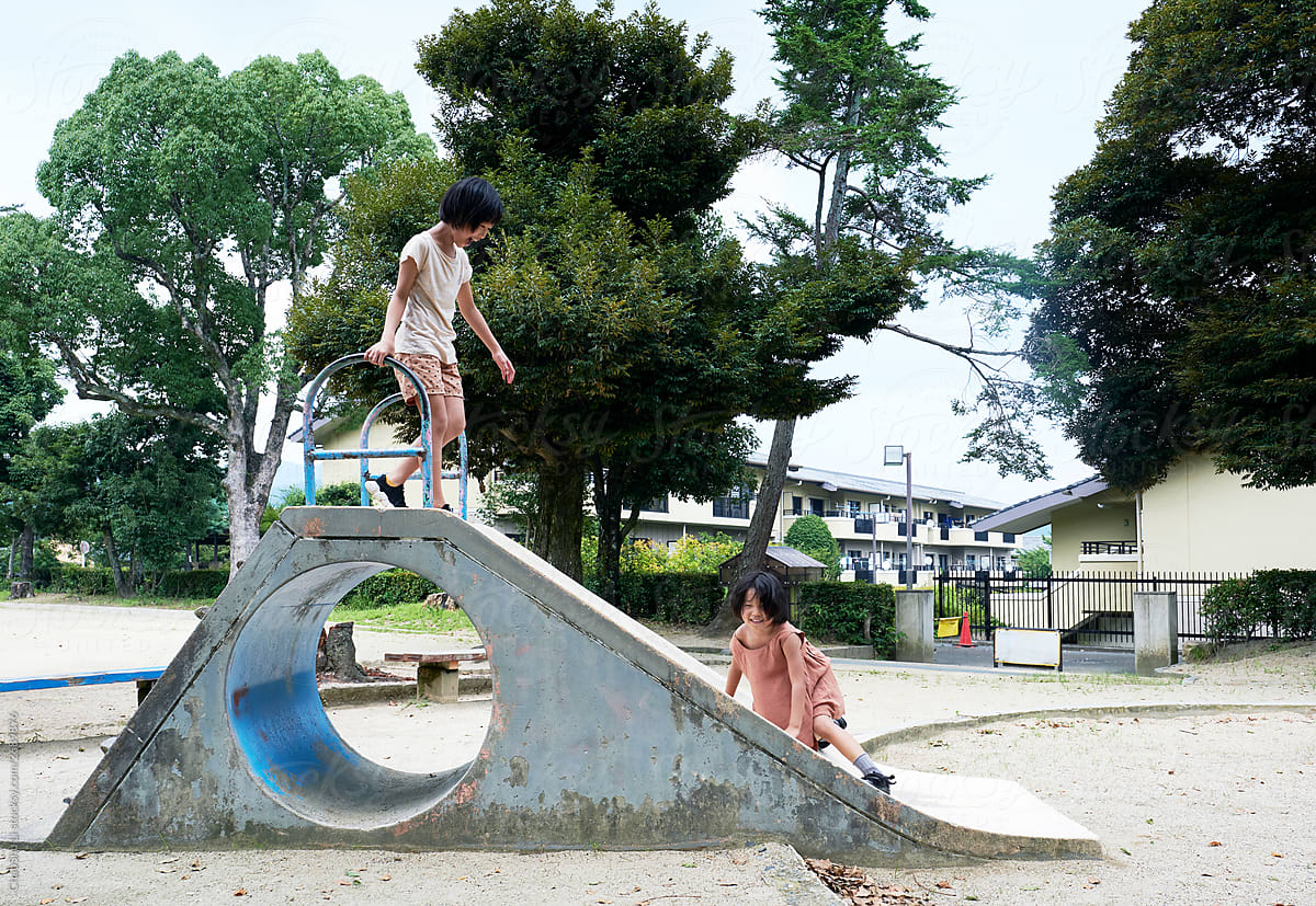Asian little girls playing slide, cute public park in Japan