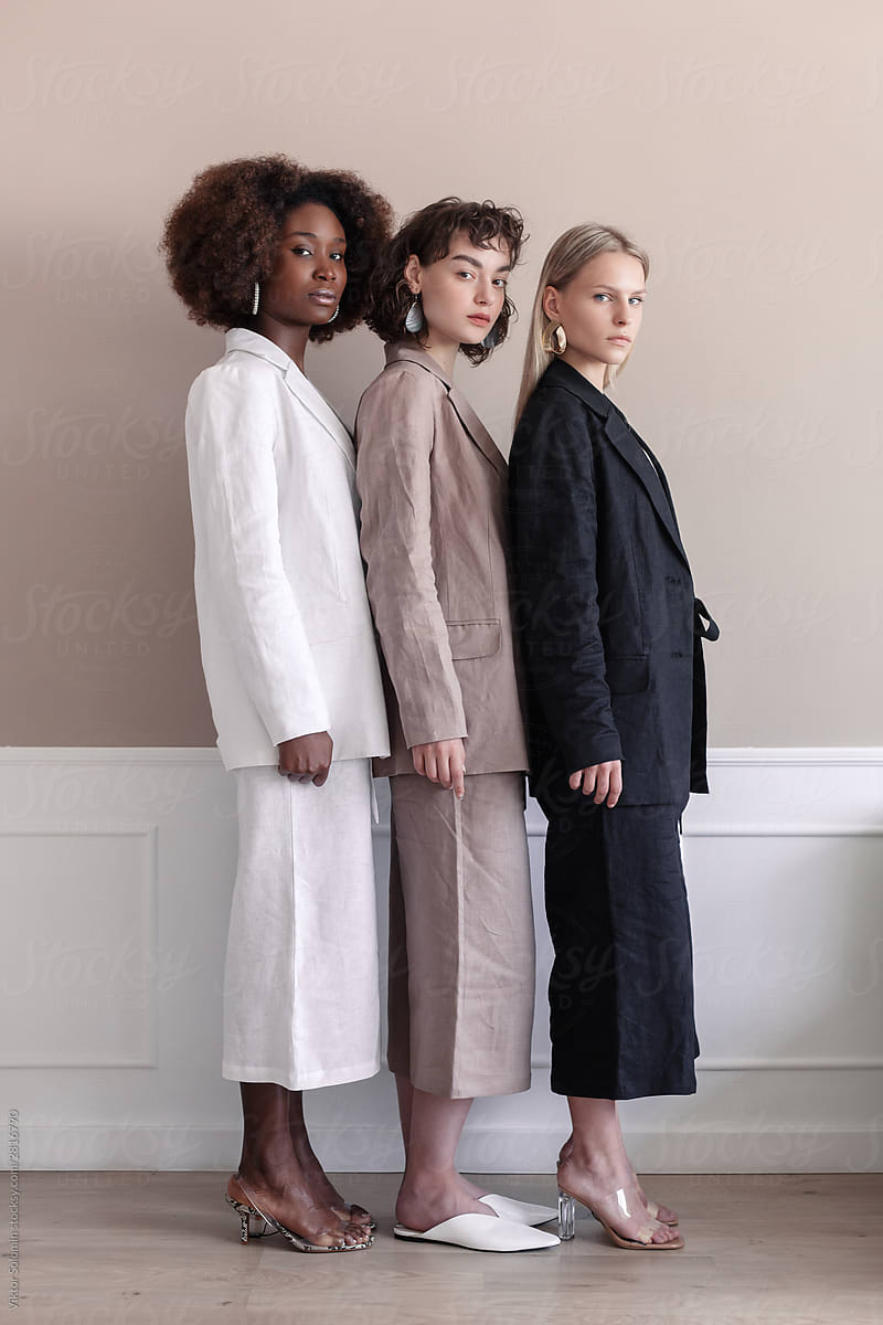 A small group of fashion multiracial multiethnic young beautiful sensual models are posing near the wall in studio room. Cultural and racial diversity concept.