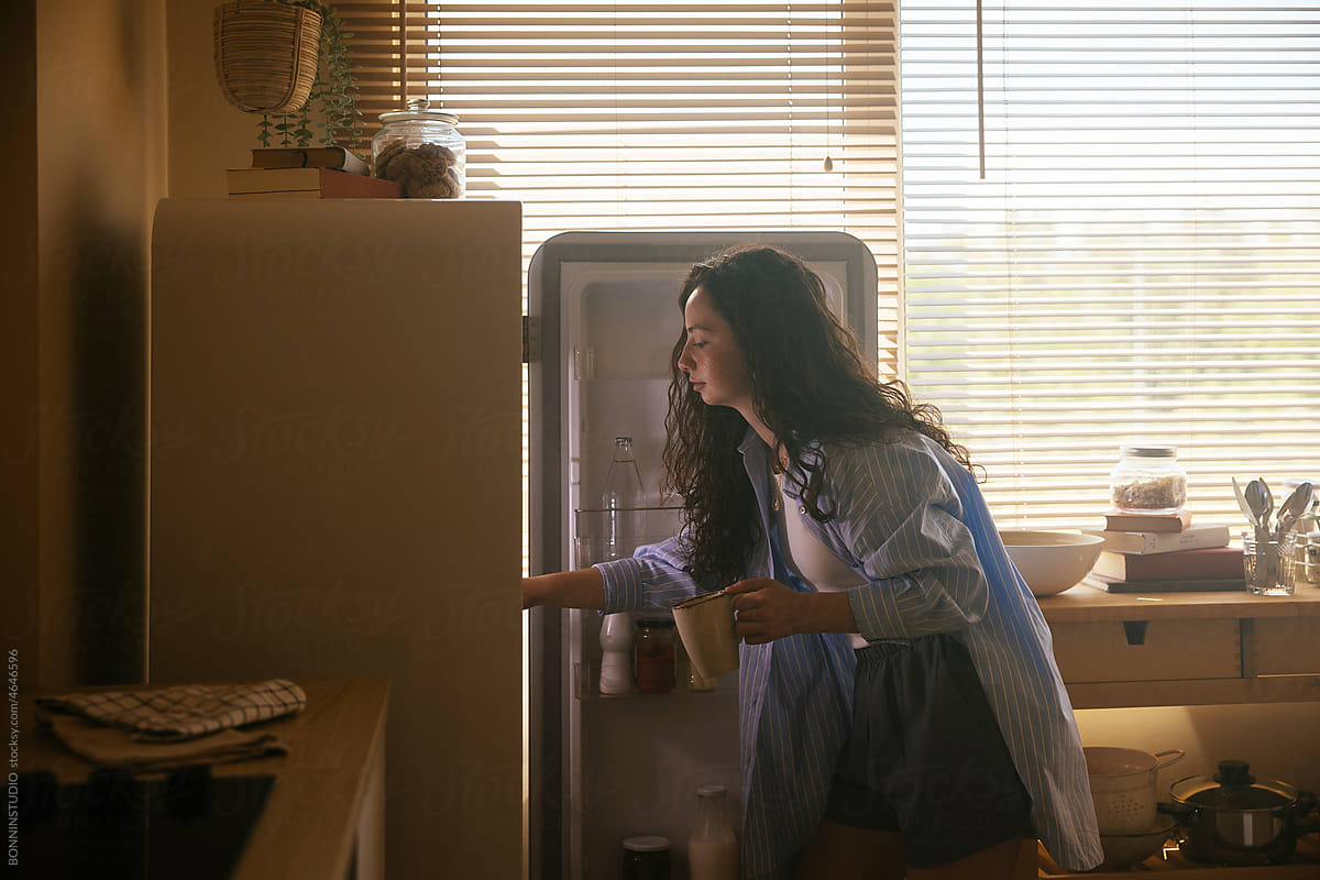 Teen girl looks into refrigerator for healthy snack