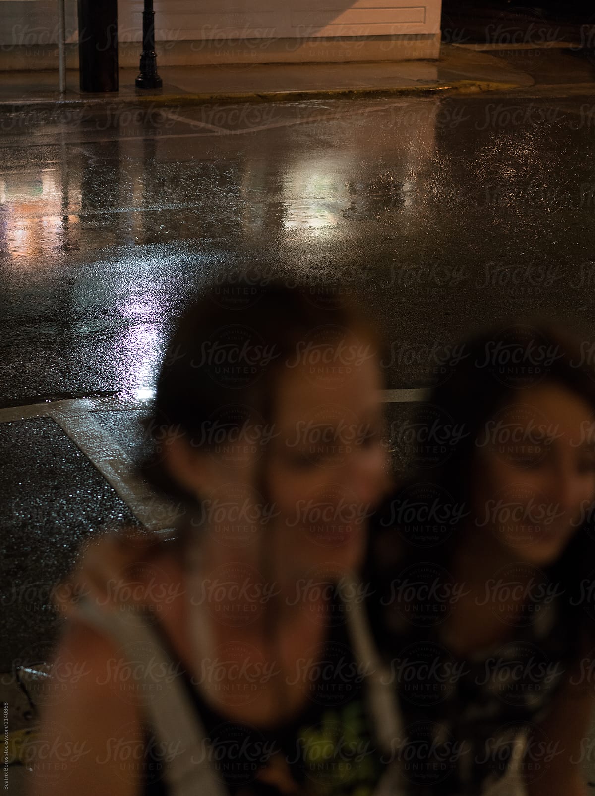 It's raining, two blurry people in the foreground
