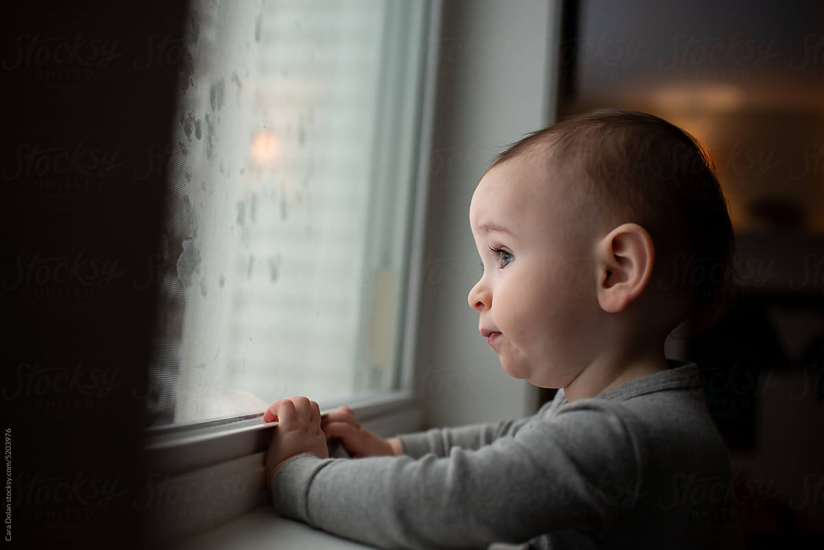 Cute baby watching out the Window at Home