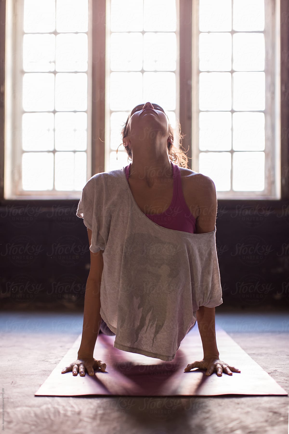 Young woman practicing in a yoga studio. Upward facing dog during sun salutations.