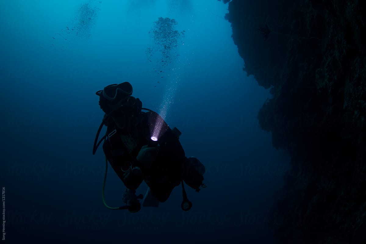 Scuba diver diving in the night with torch light