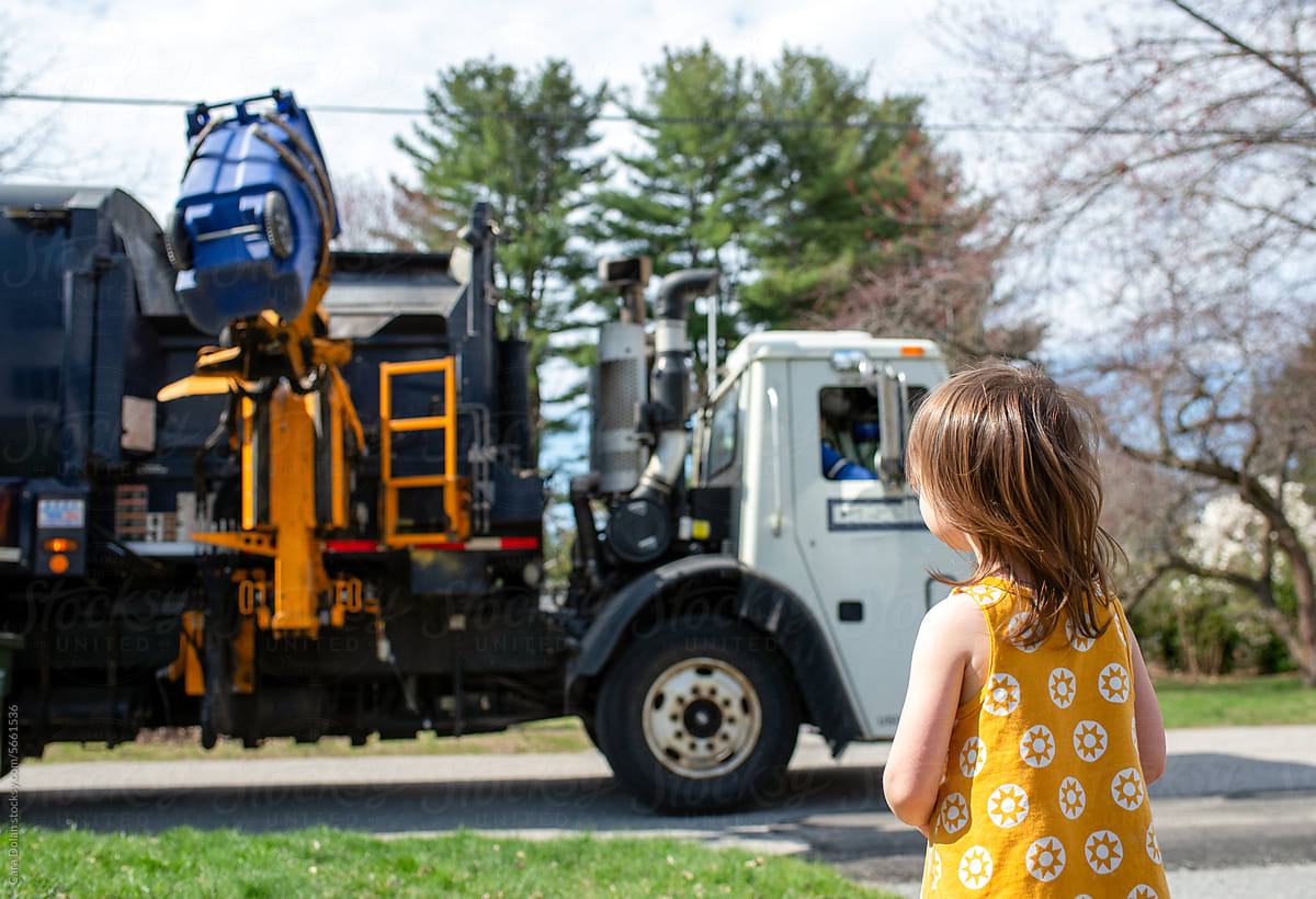 Child Watches the Garbage Truck Collect Trash Outside her House