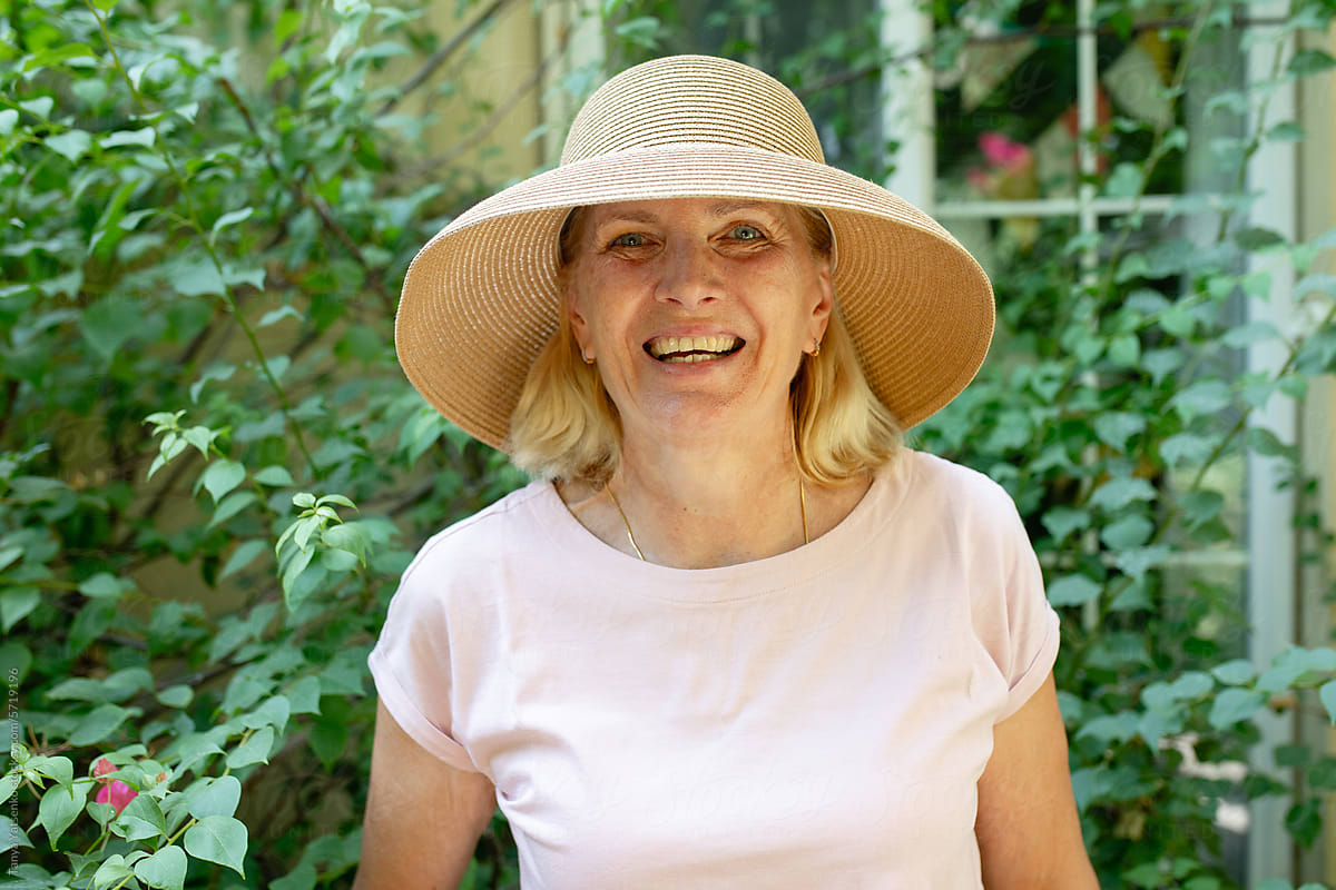 A smiling woman in a straw hat in the garden