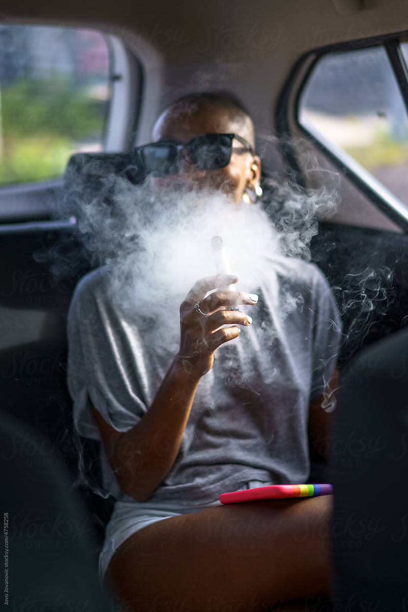 Black woman in car exhales large cloud of smoke from vape pen