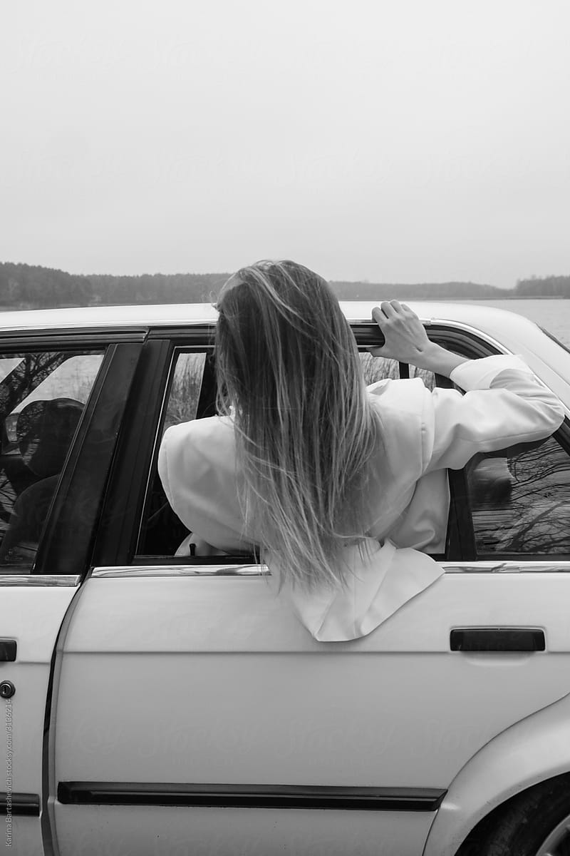 black and white photo of a girl with her hair who got out of the car window during a trip