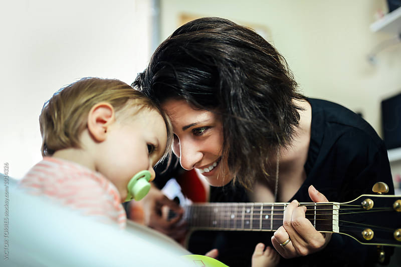 Mother Playing Guitar at Home with Her Adorable Little Girl