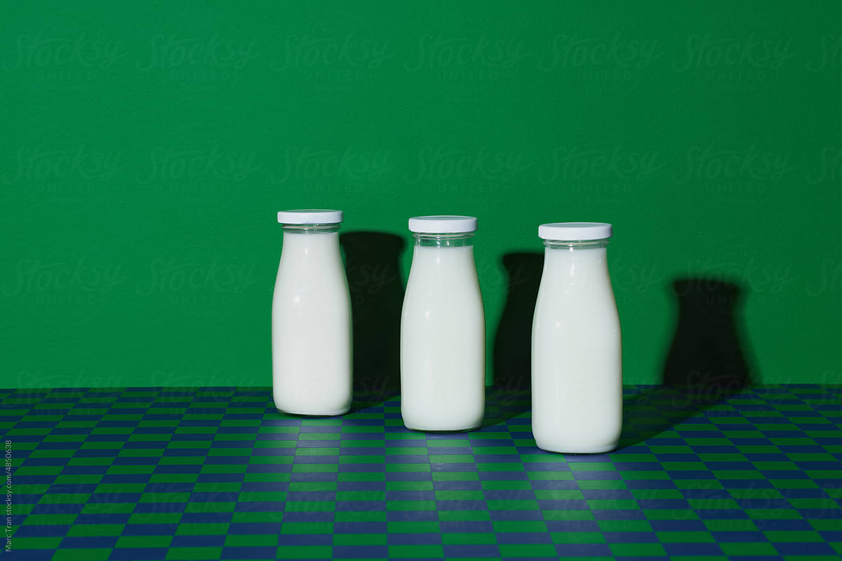 Milk in minimalism bottles with shadow on checkered background
