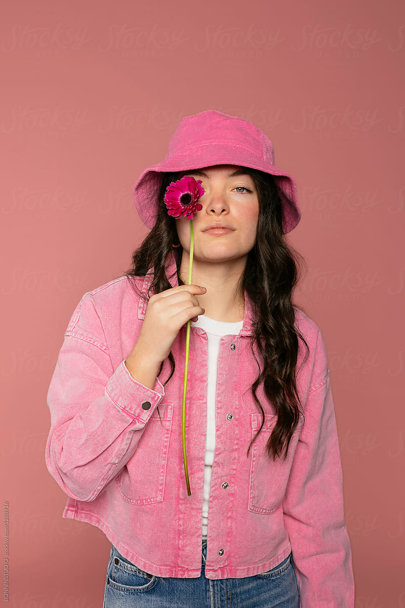 Studio portrait of woman in pink clothes holding fresh flower