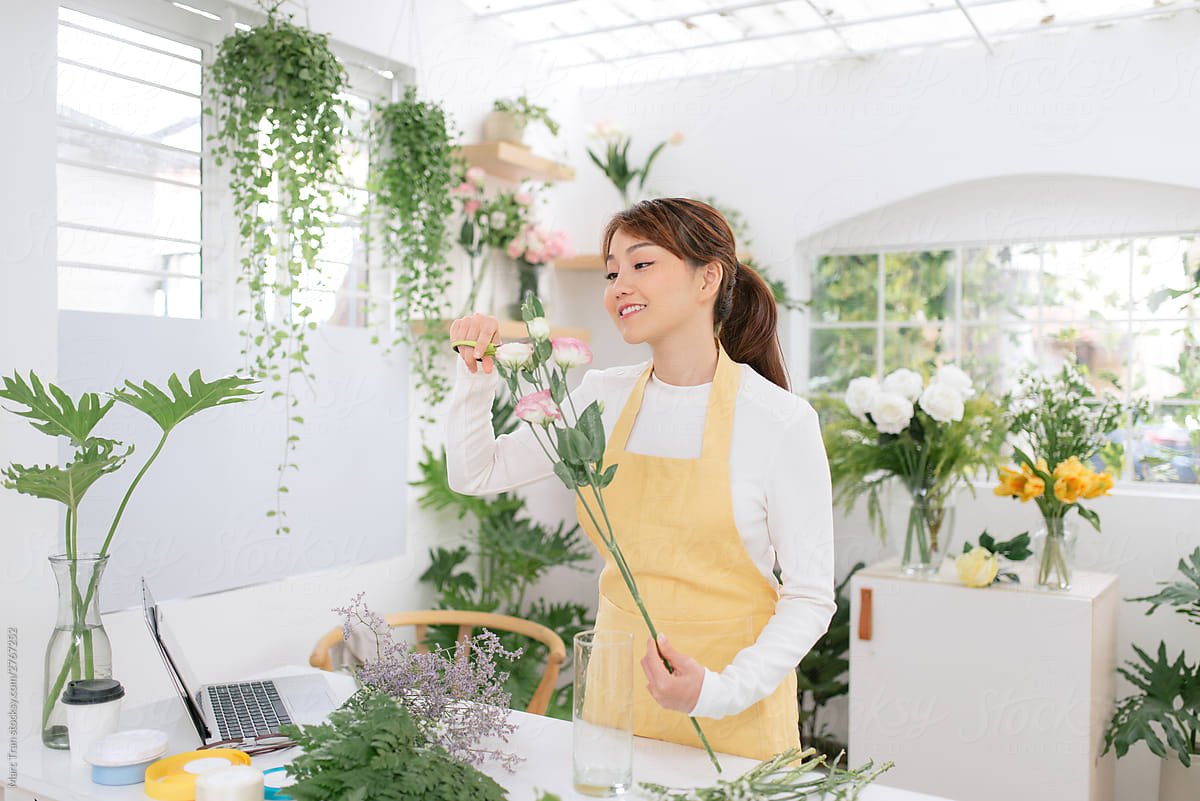 Female asian florist standing at a table in her flower
