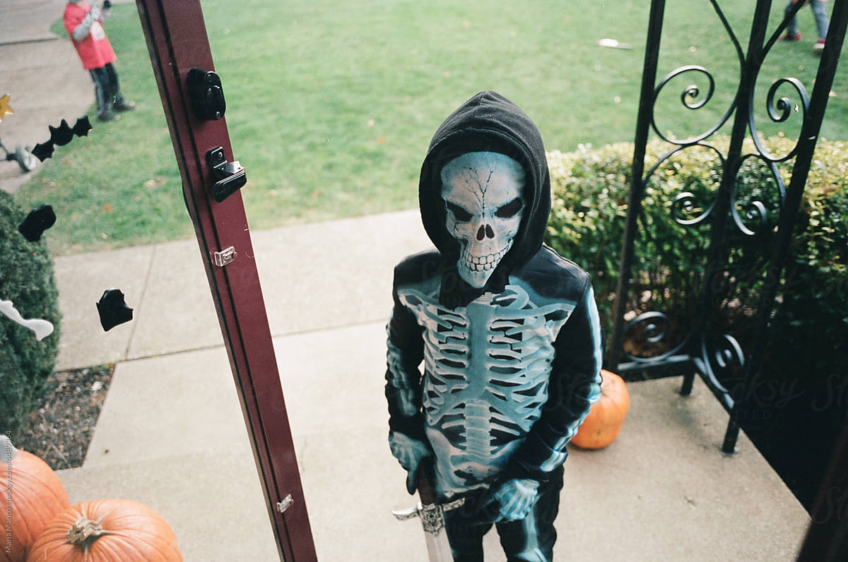 Child in skeleton costume knocks on door for halloween