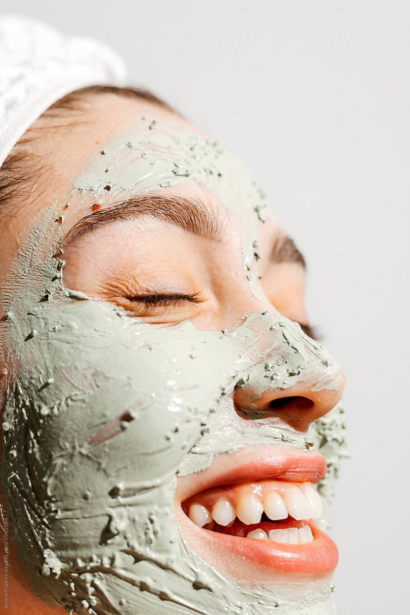 A Woman Smiling in Green Clay Mask