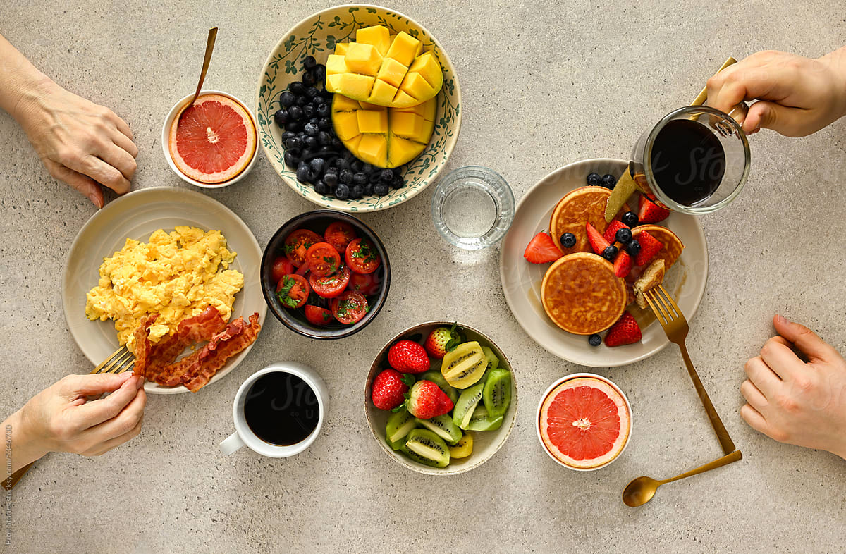People eating healthy breakfast together. Eggs, pancakes, coffee.