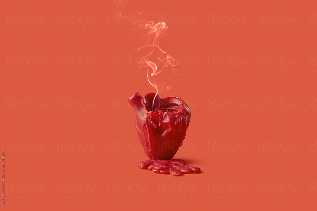 Blown out candle in shape of heart leaving drops of wax in red studio