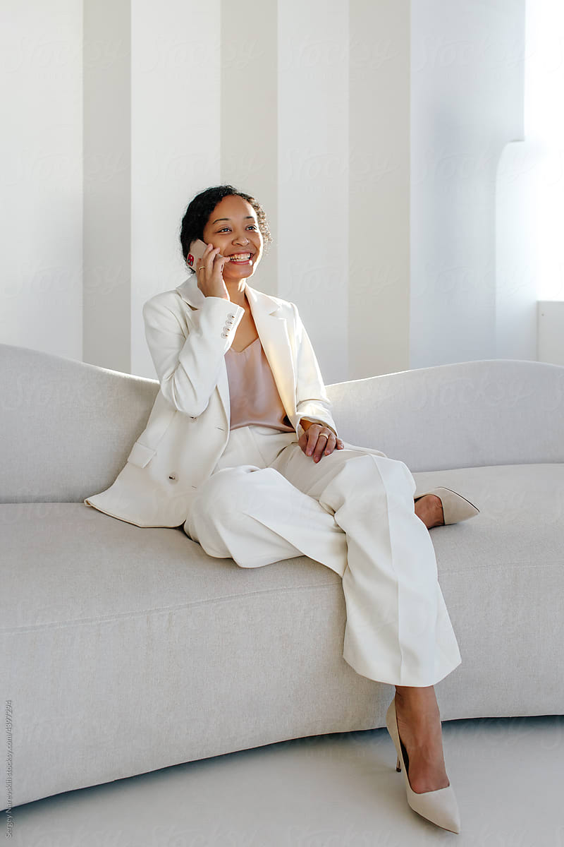 Stylish black female manager calling on phone on sofa
