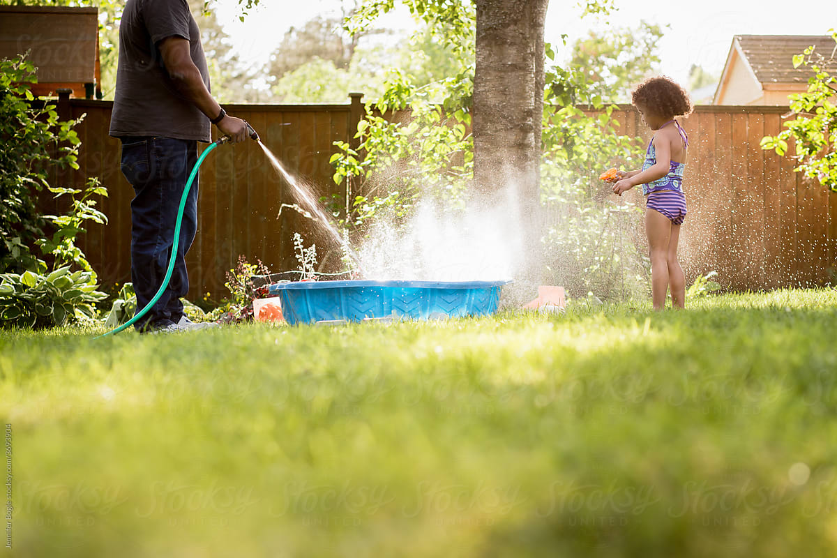 Father fills backyard pool with hose