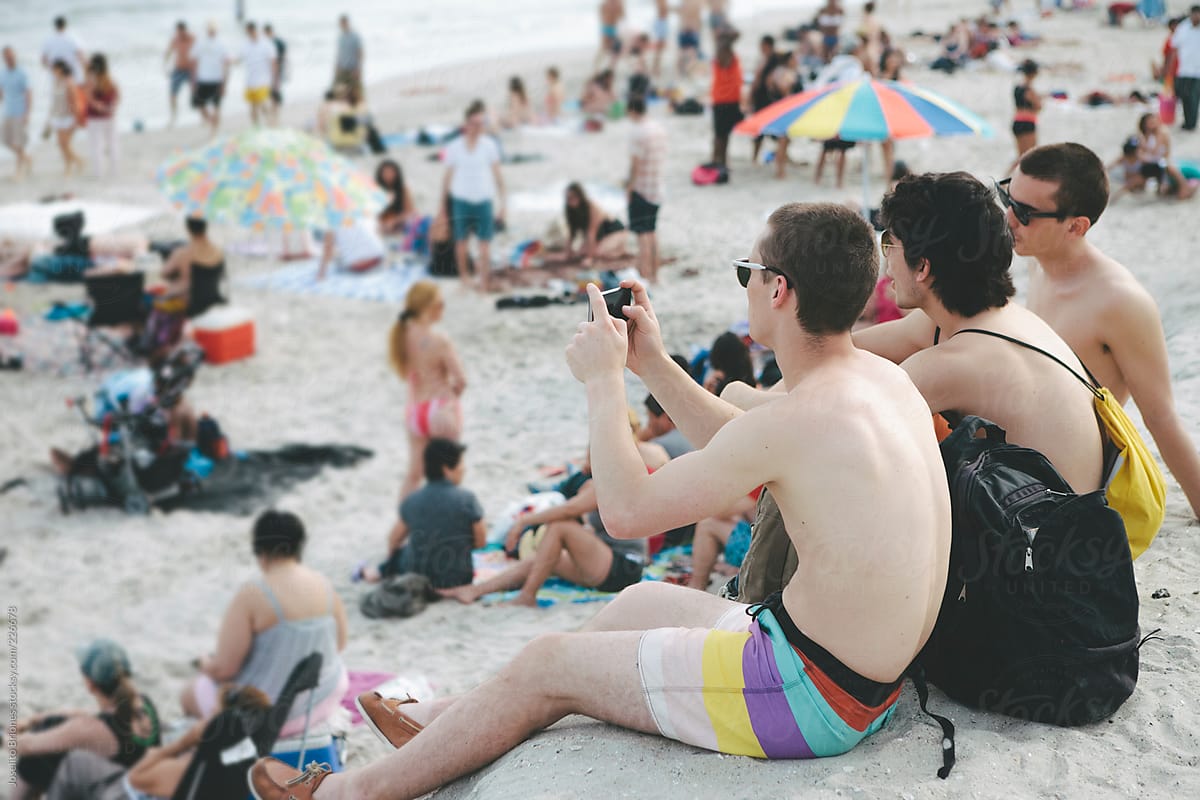 Young Men Friends Hanging Out Taking Photos with Smartphone Technology in Rockaway Beach