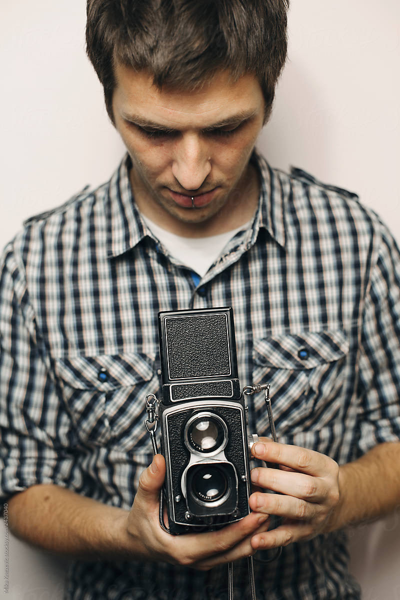 Young man holding retro analog camera