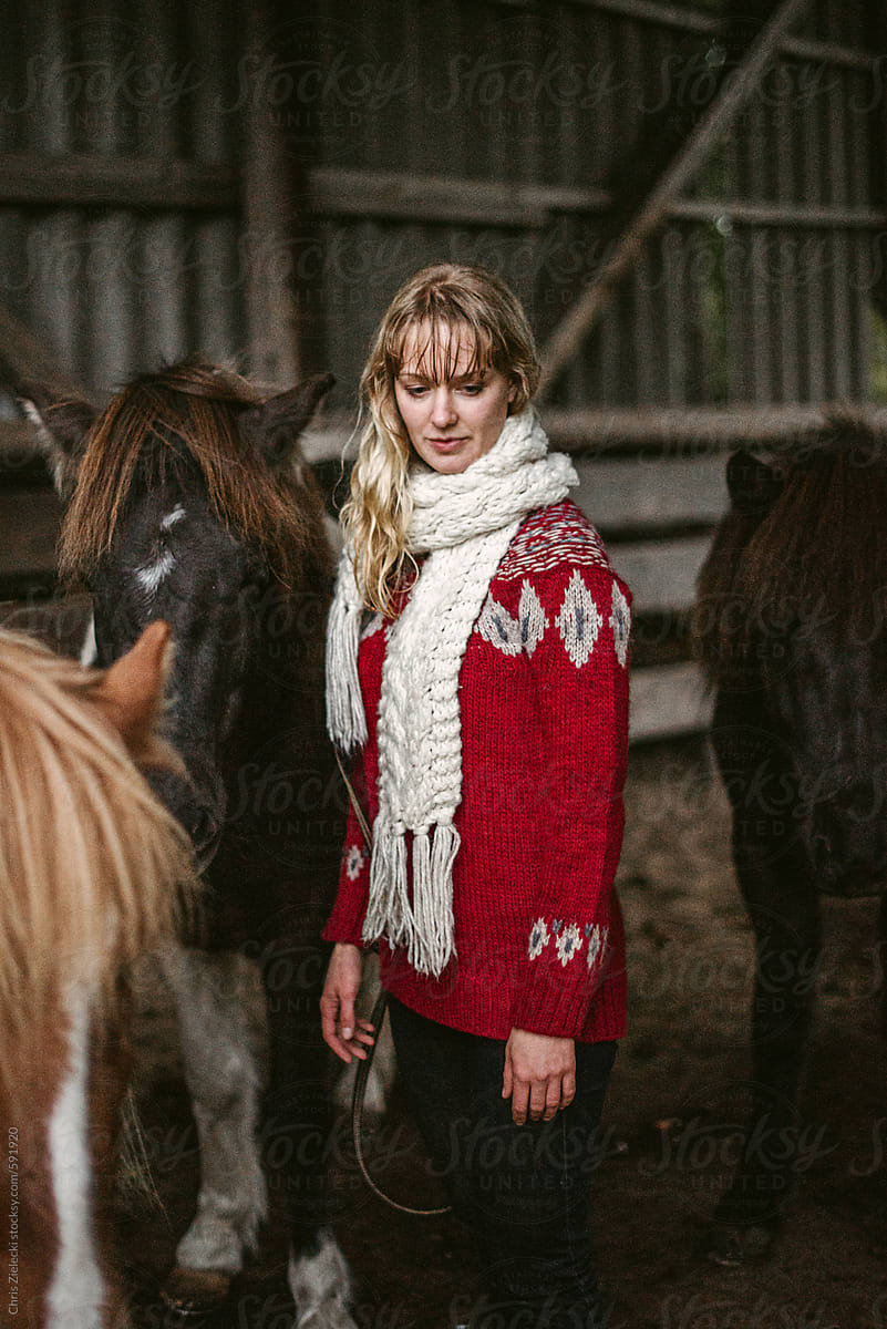 Woman visiting horses in barn