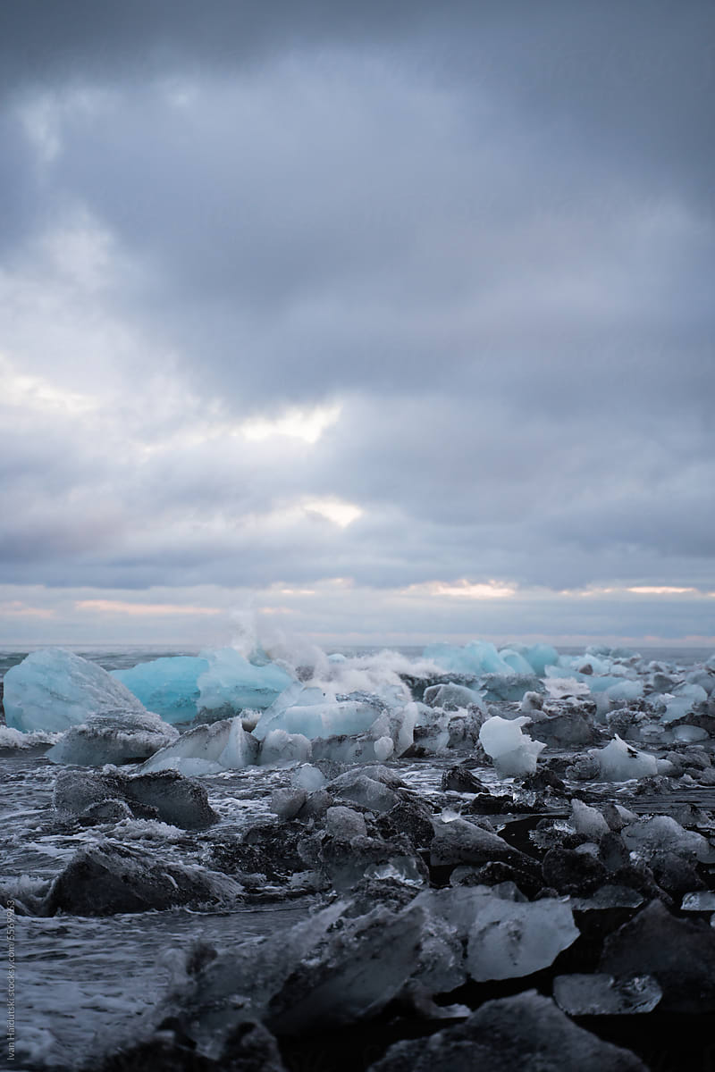 Blue icebergs and crystal ice floe blocks on wild black sand beach