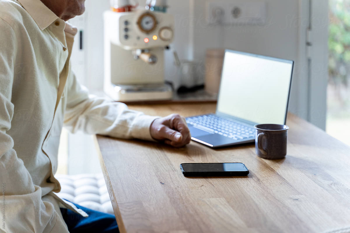 Senior man having coffee cup and using laptop