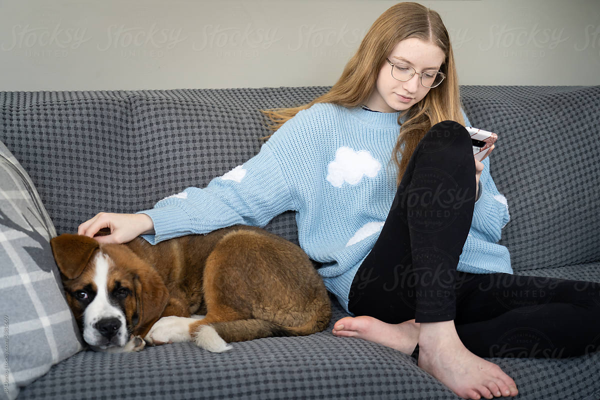 Teen Girl Looking at Phone With Large Breed Puppy Dog