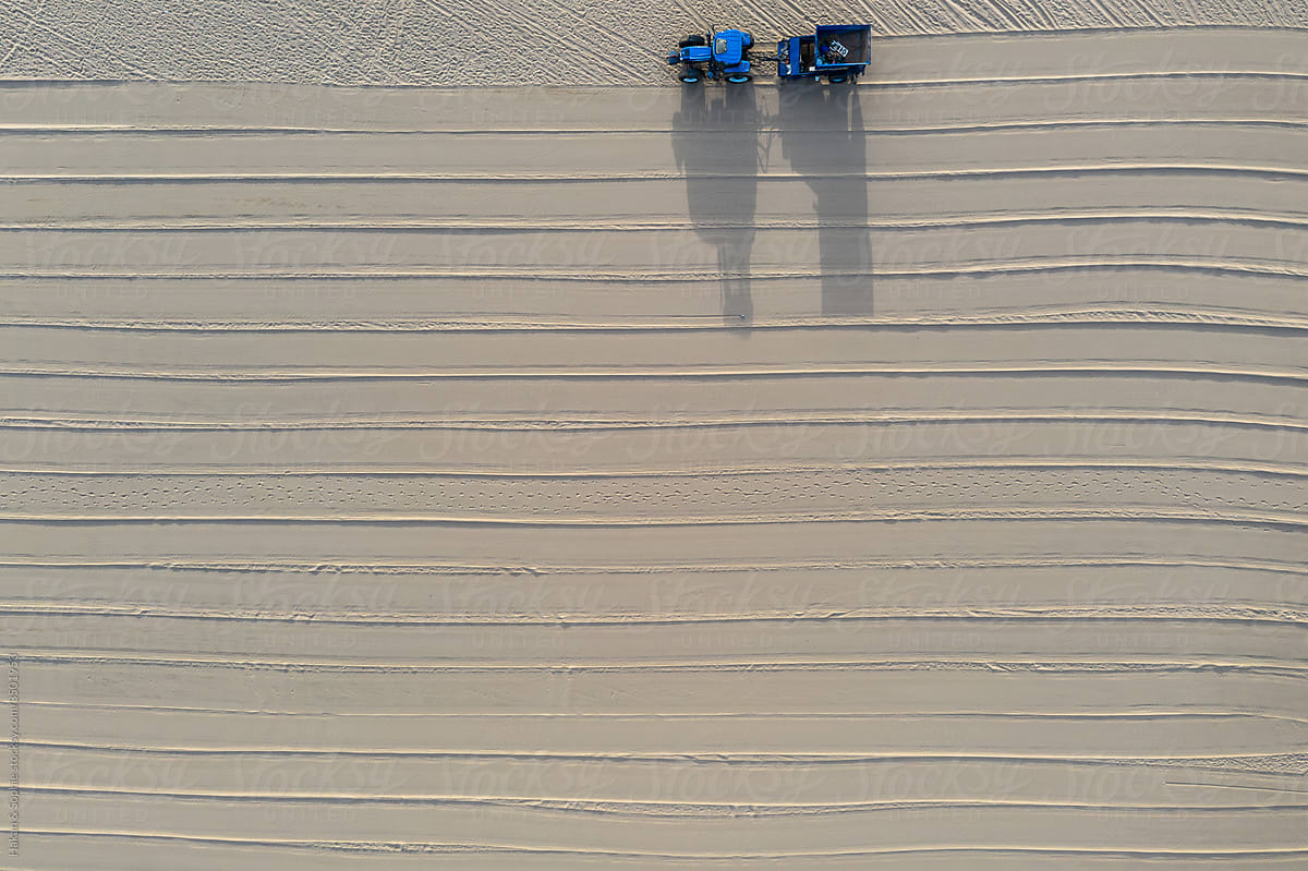 blue tractor cleaning a beach