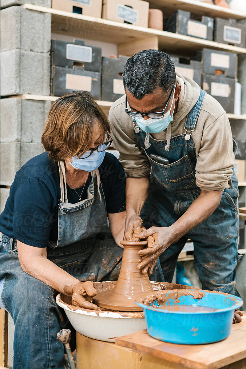Man teaching a mature woman about pottery.