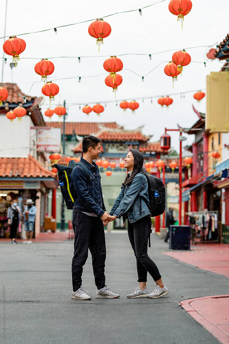 Young Asian Couple Acts Playful While Standing Under Red Lanterns in Chinatown