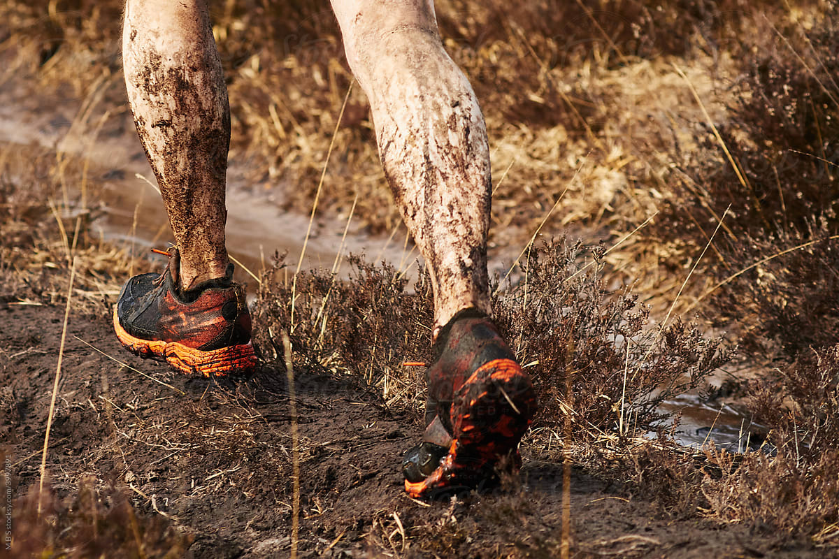 Trail runner splashes through muddy track