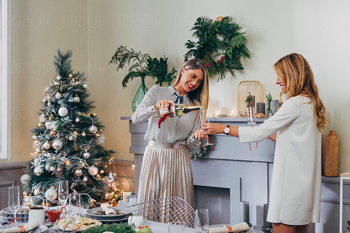 Two Women Opening Champagne Bottle at Christmas Celebration