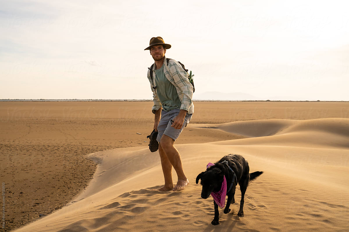 Barefoot man in desert with dog