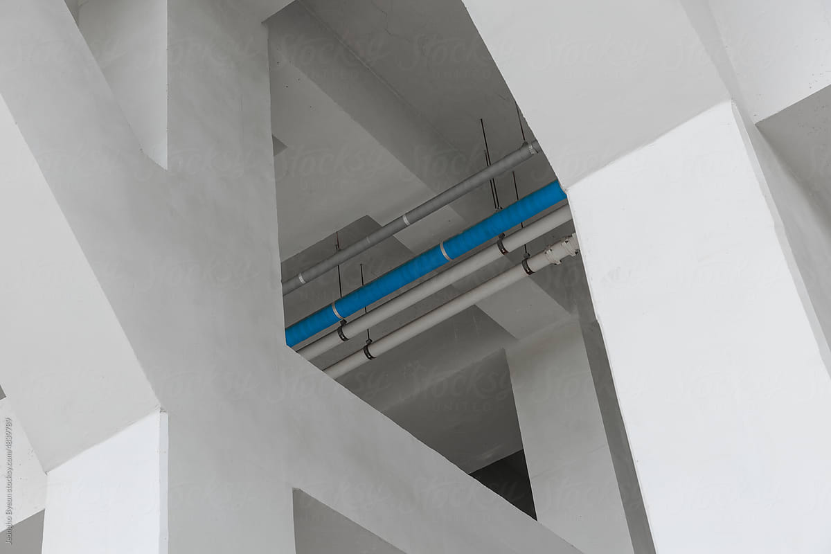 Blue pipe between columns of concrete building.