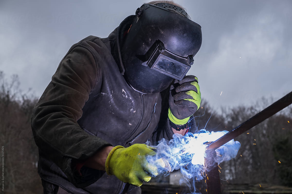 A man is welding outdoors